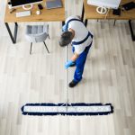 Male,janitor,mopping,floor,in,face,mask,in,office